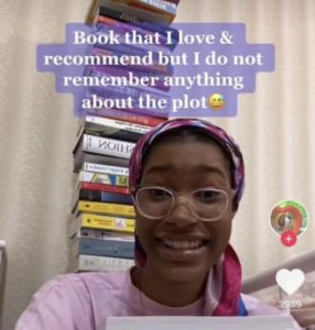 Screenshot of a TikTok featuring a young Black woman with a stack of books, captioned Book that I love & recommend but I do not remember anything about the plot